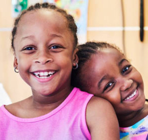 two young girls smiling and looking at the camera