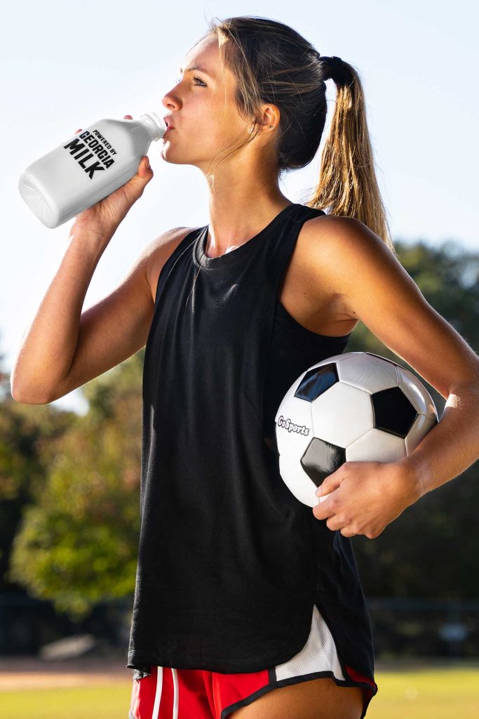college athlete drinking milk and holding a soccer ball NIL MOMM
