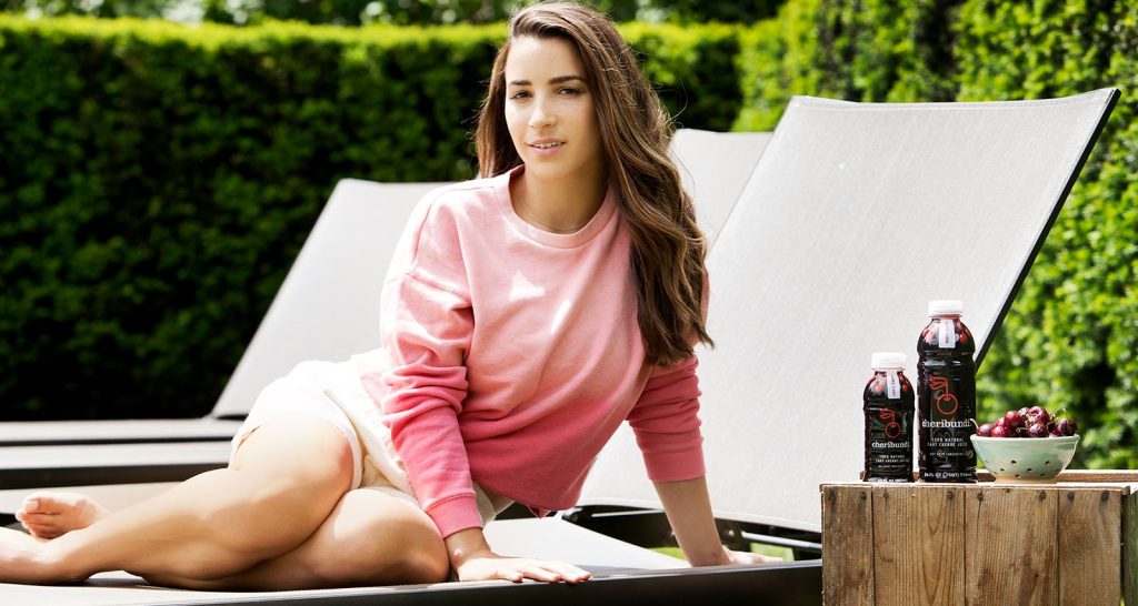 Cheribundi Ally athlete with two bottles of Cheribundi and a bowl of cherries