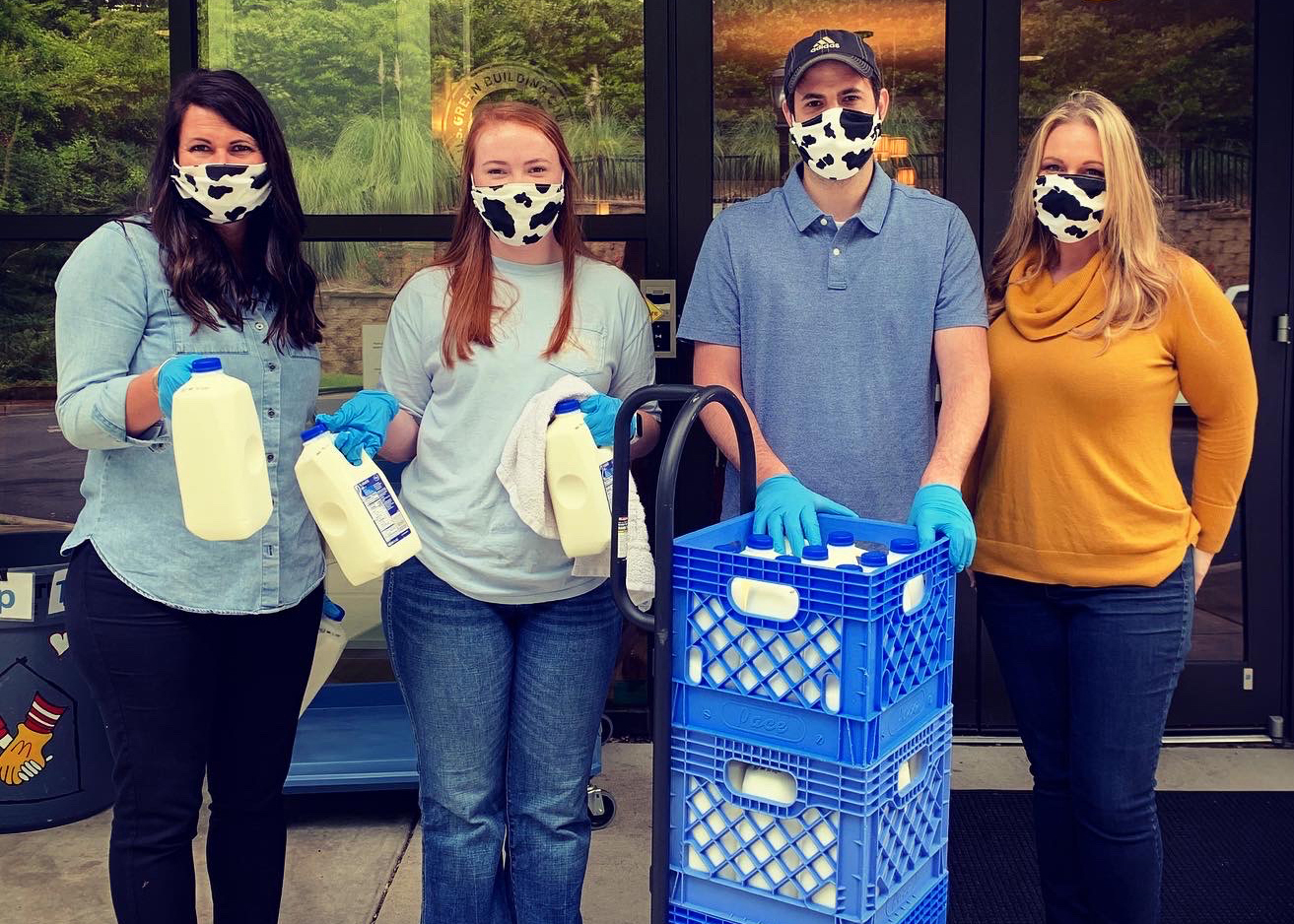 four people posing with half gallons of milk wearing cow print masks Great Georgia Give MOMM