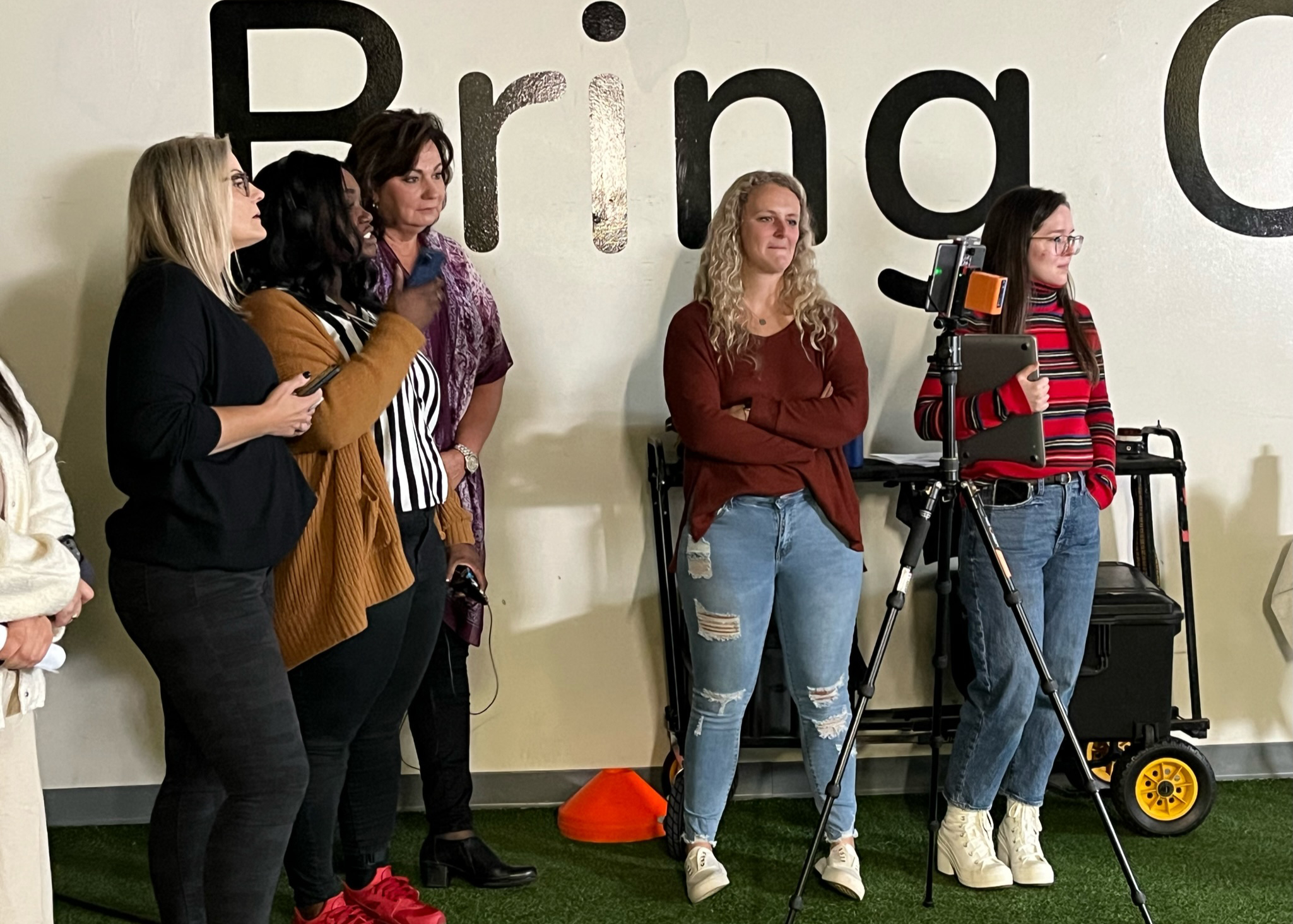 a group of women standing in front of a wall