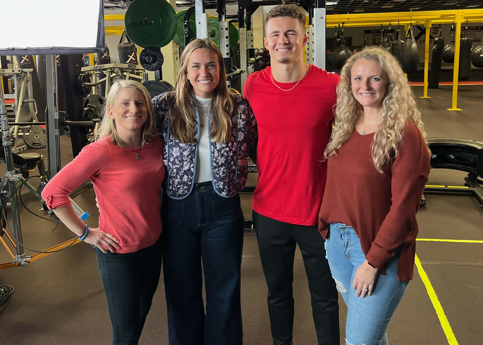 three women TPI staff members pose with college athlete MOMM