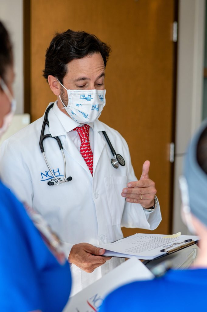 NCH All Heroes Wear Masks doctor wearing a mask talking to staff