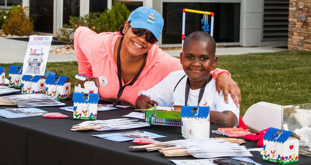 rides to remember adult woman and child at a giveaway table smiling at the camera