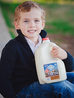 Milky Way Farm young boy holding a gallon of milk