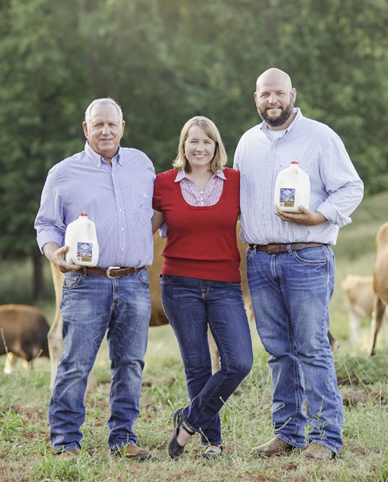 Milky Way Farm family image LD Iris and JD holding gallons of milk