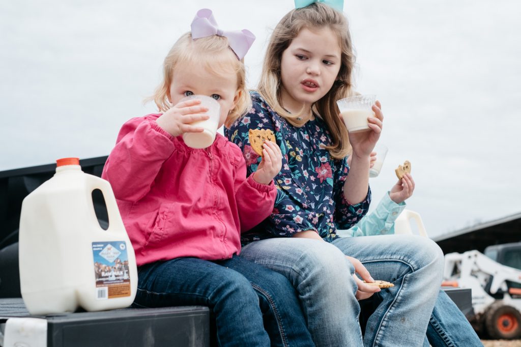 Milky Way Farm two young girls drinking milk in the back of a pick up truck and eating cookies