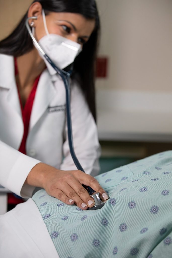 NCH NHI Phase3 Campaign female doctor with a white mask using a stethoscope on a patient