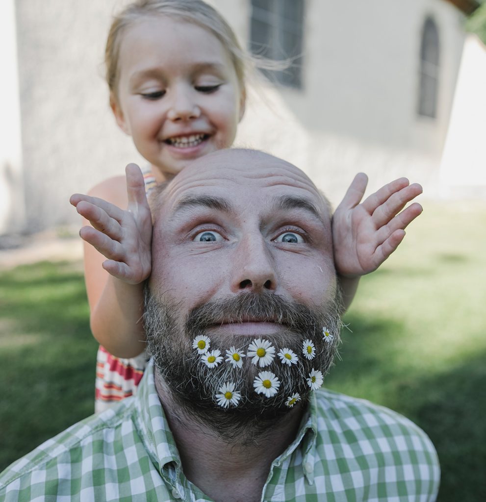 peach pass father with daisies in beard young girl behind smiling