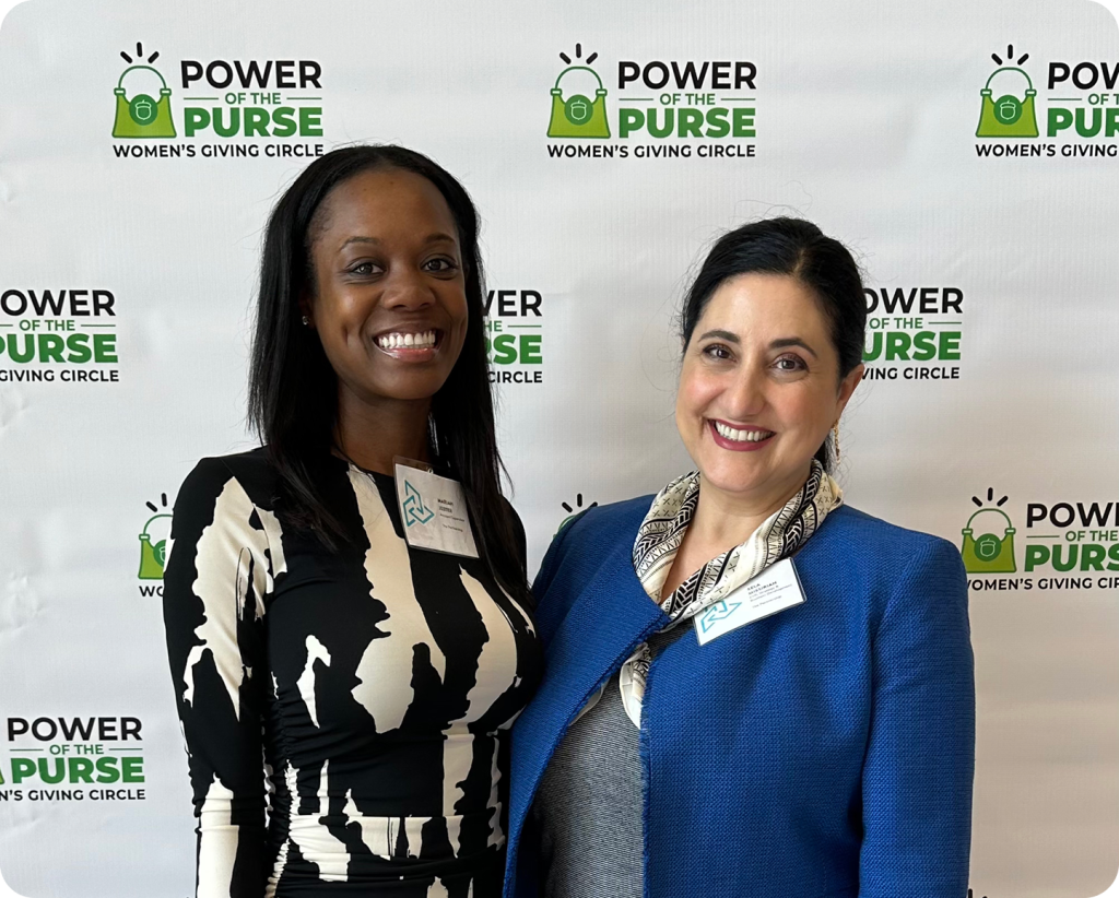 Two women posing for a photo at the Power of the Purse women's giving circle event.