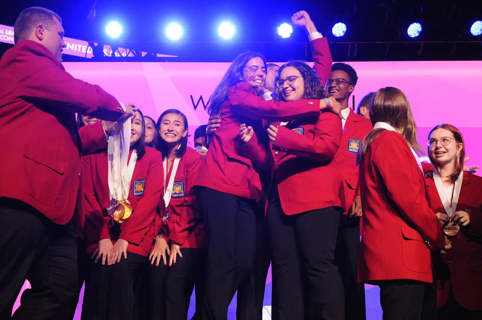 Skills USA large group of students on stage in red jackets cheering